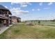Expansive backyard with lush lawn, a charming stone fire pit, and breathtaking views of the open green space at 12939 Wabash Ct, Thornton, CO 80602