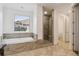 Bathroom featuring a soaking tub, a glass shower, and tiled floors, next to a toilet room at 12939 Wabash Ct, Thornton, CO 80602