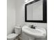 Bathroom with a pedestal sink, toilet, and modern black-framed mirror at 12939 Wabash Ct, Thornton, CO 80602