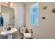 Stylish half-bathroom with modern fixtures, a pedestal sink, and a decorative mirror at 2419 Flats St, Erie, CO 80516
