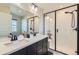 Modern bathroom featuring dual sinks, black fixtures, and a glass-enclosed shower with white subway tile at 2419 Flats St, Erie, CO 80516