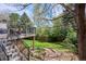 A backyard featuring a wooden deck and stairs leading to a stone walkway and lush lawn at 5320 S Geneva St, Englewood, CO 80111