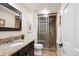 Bathroom with glass enclosed shower, dark cabinets, granite countertops, and neutral tiling at 5320 S Geneva St, Englewood, CO 80111