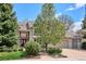Charming two-story home featuring a stone facade, red front door, and mature landscaping at 5320 S Geneva St, Englewood, CO 80111