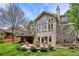 A brick two-story home features a patio with lounge chairs and a firepit in the backyard at 5320 S Geneva St, Englewood, CO 80111