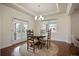 Elegant dining room with a round wooden table set for four, a modern light fixture, and French doors at 6276 S Robertsdale Ct, Aurora, CO 80016