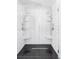 Modern bathroom shower featuring sleek white tiles, black floor tiles and dual shower heads at 3801 S Albion St, Englewood, CO 80113
