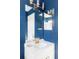 Stylish bathroom featuring a white vanity, bright gold faucet, large mirror, and modern lighting against vibrant blue walls at 9665 Bighorn Way, Littleton, CO 80125