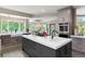 Modern kitchen island with dark cabinets, white countertop, and a view of the dining area at 11362 W Baltic Ct, Lakewood, CO 80227