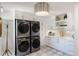 Modern laundry room with stacked washer and dryer, shaker cabinets, and herringbone backsplash at 11362 W Baltic Ct, Lakewood, CO 80227