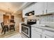 Modern kitchen with stainless steel appliances and white cabinets adjacent to the dining area with wood-burning fireplace at 9967 Lane St, Thornton, CO 80260