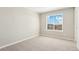 A bright bedroom with neutral carpet, paint, and trim, and a large window that lets in ample natural light at 9484 Yampa St, Commerce City, CO 80022