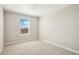 A bright bedroom with neutral carpet, paint, and trim, and a large window that lets in ample natural light at 9484 Yampa St, Commerce City, CO 80022