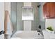 Modern bathroom featuring gray tiled walls, a showerhead, tub, and a dark wood cabinet for storage at 2731 W 42Nd Ave, Denver, CO 80211