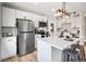 Modern kitchen with stainless steel refrigerator, white cabinets, island with seating, and updated lighting at 2731 W 42Nd Ave, Denver, CO 80211