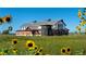 Charming farmhouse-style property framed by sunflowers and a picturesque country landscape at 2108 Chambers Rd, Brighton, CO 80601