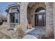 Inviting entryway featuring a brick archway, decorative glass door, and a cozy wooden bench, surrounded by decorative landscaping at 5284 Taft Ct, Arvada, CO 80002