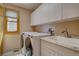 Bright laundry room featuring white washer and dryer, granite counters, and window at 5284 Taft Ct, Arvada, CO 80002
