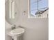 Half bathroom featuring a pedestal sink with round mirror and a window at 7213 Waterleaf Trl, Littleton, CO 80125
