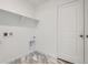 Bright laundry room with marble-look floors, upper shelf, and utility connections for washer and dryer hookups at 7213 Waterleaf Trl, Littleton, CO 80125