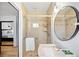 Tiled bathroom with a glass-enclosed shower, a round mirror, and modern fixtures at 6211 E Orchard Dr, Greenwood Village, CO 80111