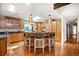 Well-lit kitchen boasts custom wood cabinets, hardwood floors, an island with bar seating, and stainless steel appliances at 6211 E Orchard Dr, Greenwood Village, CO 80111