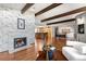 Open concept living area with exposed wood beams, a modern fireplace, and wood floors that flow into the kitchen at 6211 E Orchard Dr, Greenwood Village, CO 80111
