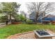 Well-manicured backyard featuring lush lawn, a wooden fence, and a brick fire pit area at 6647 Lynx Cv, Lone Tree, CO 80124
