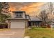 Charming two-story home with a brick-accented garage, solar panels and well-manicured front lawn against a colorful sunset at 6647 Lynx Cv, Lone Tree, CO 80124