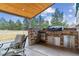 Covered outdoor kitchen with stone counters and stainless steel appliances at 23469 E Briarwood Pl, Aurora, CO 80016