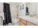 Bathroom featuring tile floors, a shower with black and white curtain, and a sink with wooden cabinets at 16665 Kenuil St, Brighton, CO 80603