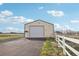 Exterior of the large metal garage featuring a high roll up door and a solid side door at 16665 Kenuil St, Brighton, CO 80603