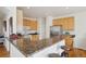 Open kitchen featuring a breakfast bar with granite countertops, wood cabinetry, and stainless steel appliances at 16665 Kenuil St, Brighton, CO 80603