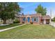Charming brick home with bright blue door and shutters with grassy front lawn at 1691 Roslyn St, Denver, CO 80220