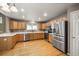 Well-lit kitchen featuring stainless steel appliances, wood cabinets, quartz counters, and hardwood floors at 13313 Elizabeth St, Thornton, CO 80241