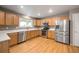 Well-lit kitchen featuring stainless steel appliances, wood cabinets, quartz counters, and hardwood floors at 13313 Elizabeth St, Thornton, CO 80241