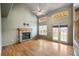 Inviting living room featuring a brick fireplace, hardwood floors, a ceiling fan, and access to the backyard at 13313 Elizabeth St, Thornton, CO 80241