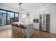 A modern white kitchen features an island with seating, stainless appliances, and a large window with city views at 1750 Wewatta St # 1720, Denver, CO 80202