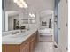 Bright bathroom with double sinks, wood cabinets, and an arched doorway to the bedroom at 5079 Morning Glory Pl, Highlands Ranch, CO 80130