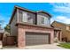 The exterior showcases a combination of brick and siding, a two-car garage, and a well-manicured lawn at 5079 Morning Glory Pl, Highlands Ranch, CO 80130