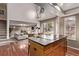 Bright kitchen features a center island with cooktop, hardwood floors and an open view to the living room at 5079 Morning Glory Pl, Highlands Ranch, CO 80130