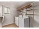 Practical laundry room with washer, dryer, shelving and natural light at 5079 Morning Glory Pl, Highlands Ranch, CO 80130