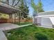 Backyard features lush green grass, a stained fence, detached garage, and covered patio at 386 Colorado Blvd, Denver, CO 80206