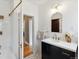 Modern bathroom with black and gold fixtures, black vanity, white countertop, and a view into an adjacent room with patterned wallpaper at 386 Colorado Blvd, Denver, CO 80206