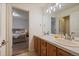 Bright bathroom featuring a double sink vanity with tile countertop and wood cabinets next to the main bedroom at 7829 S Coolidge Way, Aurora, CO 80016