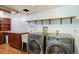 Functional laundry room with front loading washer and dryer with storage cabinets and workspace at 7629 S Fillmore Way, Centennial, CO 80122