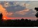 Bright sunset with orange and red skies over a treeline and hints of mountain range at 7629 S Fillmore Way, Centennial, CO 80122
