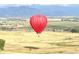 Vibrant red hot air balloon floats over scenic landscape with mountain views at 227 Powderhorn Trl, Broomfield, CO 80020