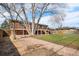 A view of the brick home's backyard, featuring a blend of gravel and lawn, enhanced by mature trees at 5862 Owens St, Arvada, CO 80004