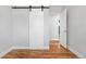 Bright bedroom featuring hardwood floors, a sliding barn door, and a view into the next room at 5862 Owens St, Arvada, CO 80004